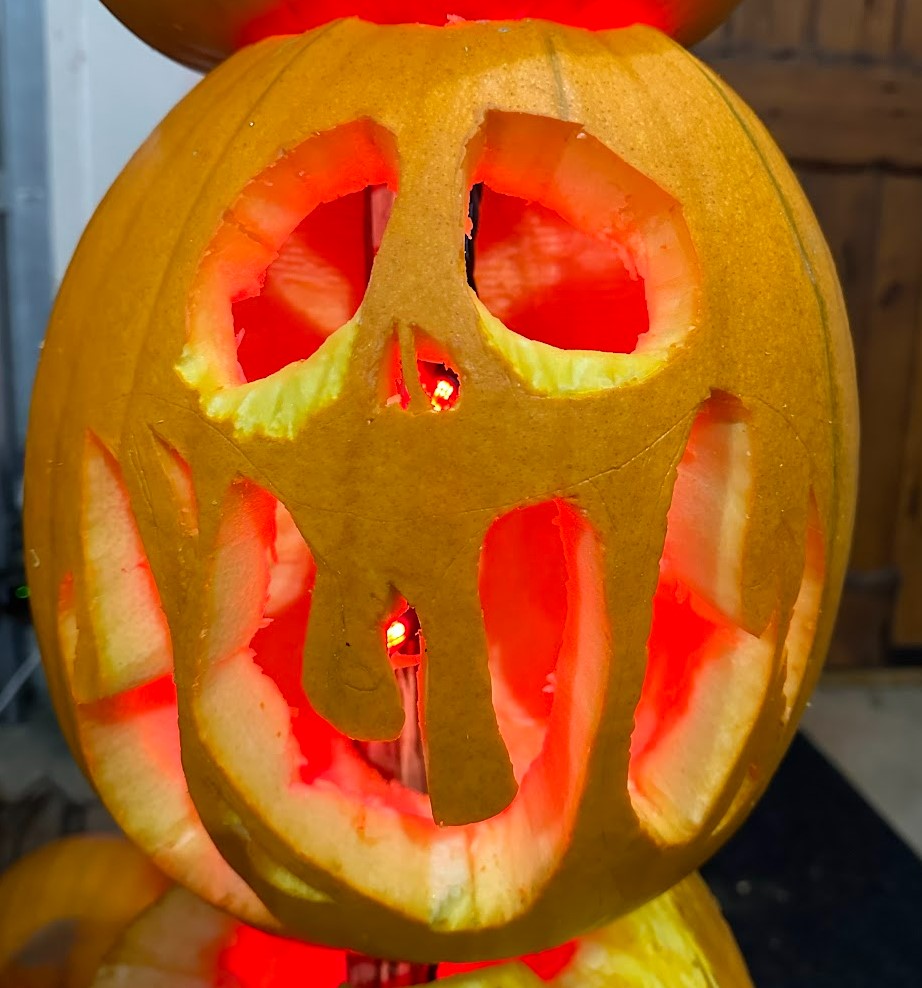 A jack-o'-lantern with a funky face lit up by string lights.