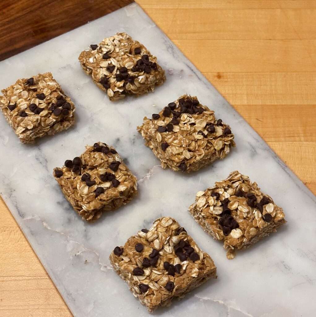 A picture of six oat bars on a marble cutting board.