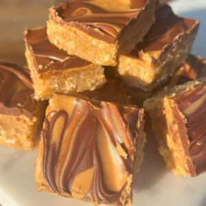A close up of square peanut butter and chocolate swirl oat bars on a marble tray.