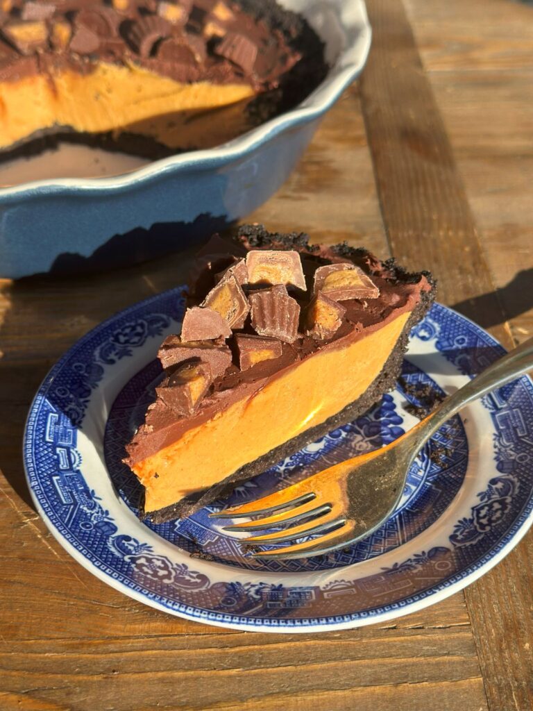 The Easiest No-Bake Peanut Butter Pie With Oreo Crust on a Plate in Front of the Rest of the Pie.