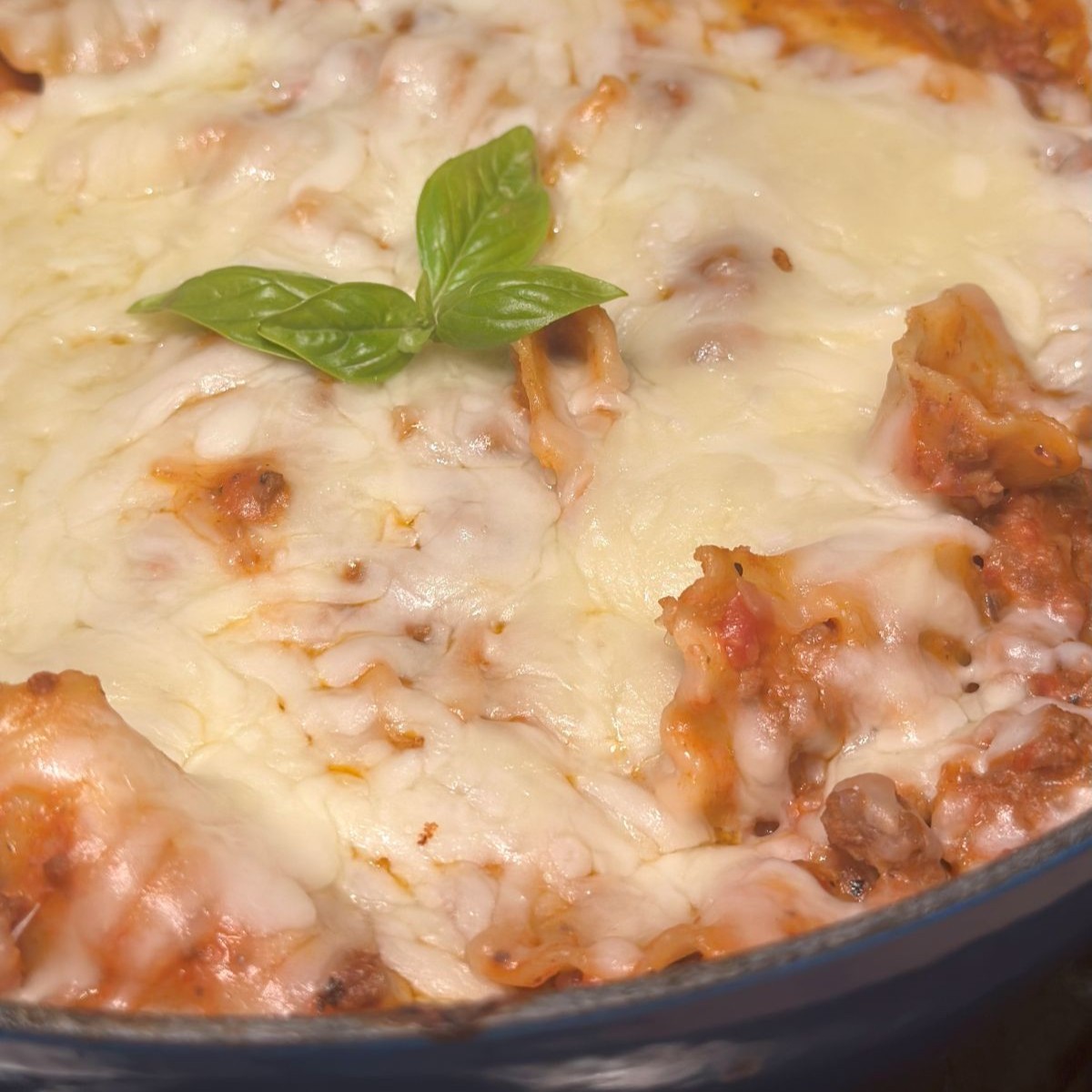 A close up of the skillet lasagna, with lots of cheese and garnished with some fresh basil.